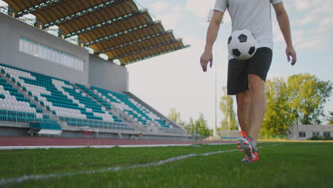 Professional-Male-soccer-player-athlete-on-the-football-field-in-slow-motion-in-sports-equipment-juggles-a-soccer-ball.-A-soccer-player-with-a-ball-in-the-stadium-near-the-keepy-uppies-stands